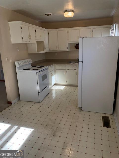 kitchen with white cabinetry, sink, and white appliances