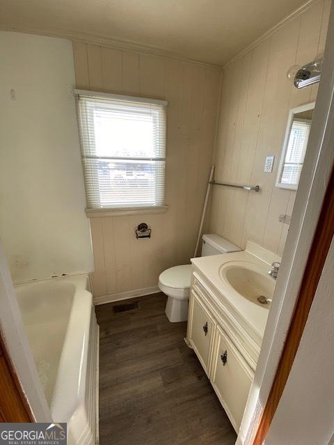 bathroom featuring vanity, wood-type flooring, toilet, and a healthy amount of sunlight