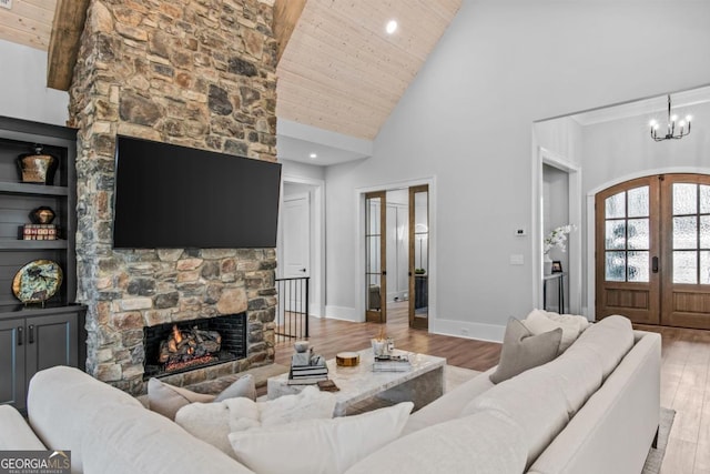 living room with wood ceiling, an inviting chandelier, a fireplace, french doors, and light wood-type flooring