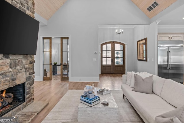 living room featuring light hardwood / wood-style flooring, a fireplace, wood ceiling, and french doors