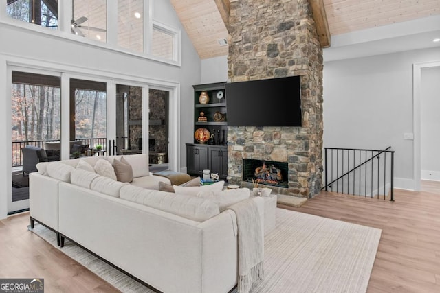 living room with a stone fireplace, high vaulted ceiling, beamed ceiling, wood ceiling, and light hardwood / wood-style floors