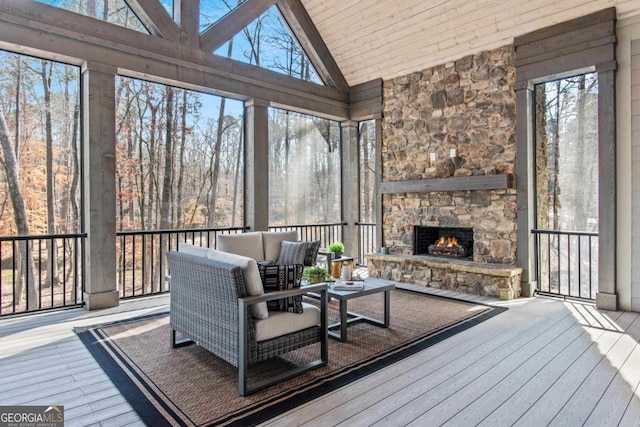 sunroom featuring an outdoor stone fireplace, vaulted ceiling, and a wealth of natural light