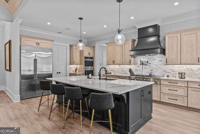 kitchen featuring custom exhaust hood, decorative light fixtures, a kitchen breakfast bar, an island with sink, and stainless steel appliances