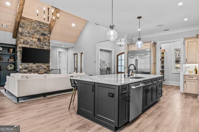 kitchen featuring sink, decorative light fixtures, a kitchen island with sink, stainless steel appliances, and light hardwood / wood-style floors