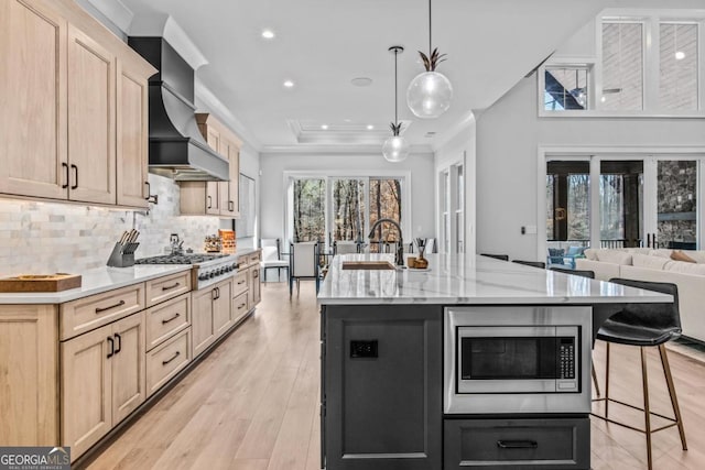 kitchen featuring stainless steel appliances, premium range hood, a large island, and decorative light fixtures