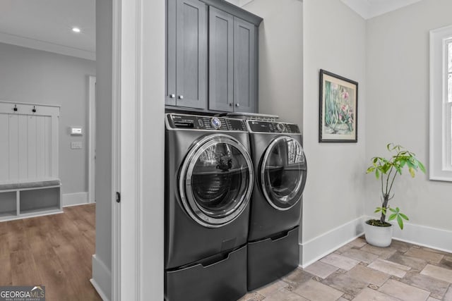 clothes washing area with cabinets, ornamental molding, and washer and clothes dryer