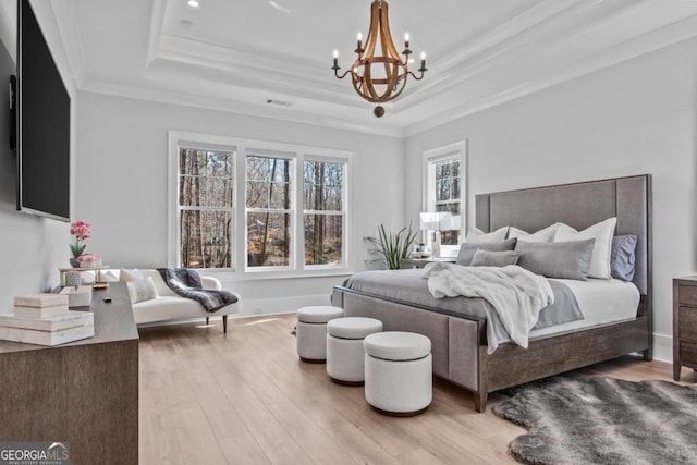 bedroom featuring an inviting chandelier, a tray ceiling, ornamental molding, and hardwood / wood-style flooring