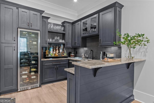 bar featuring sink, light hardwood / wood-style flooring, gray cabinetry, wine cooler, and tasteful backsplash