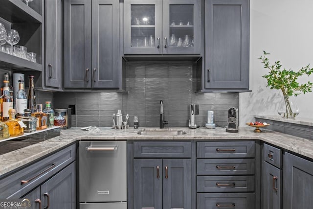 kitchen with light stone countertops, sink, gray cabinetry, and decorative backsplash