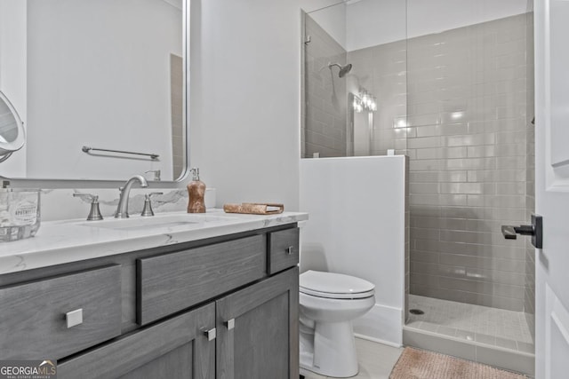 bathroom with vanity, toilet, and a tile shower