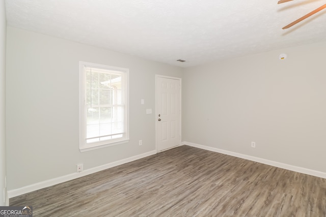 unfurnished room with a textured ceiling, wood-type flooring, and ceiling fan