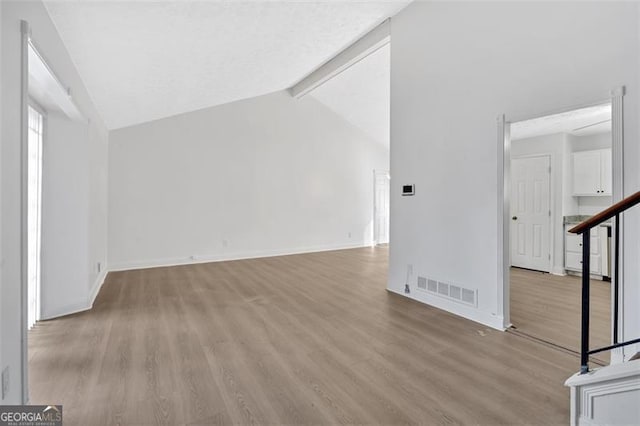 interior space with light hardwood / wood-style flooring and vaulted ceiling with beams