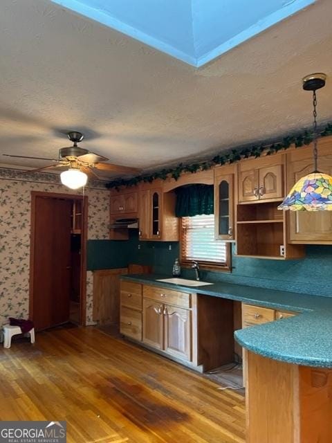 kitchen featuring sink, wood-type flooring, a textured ceiling, pendant lighting, and range hood