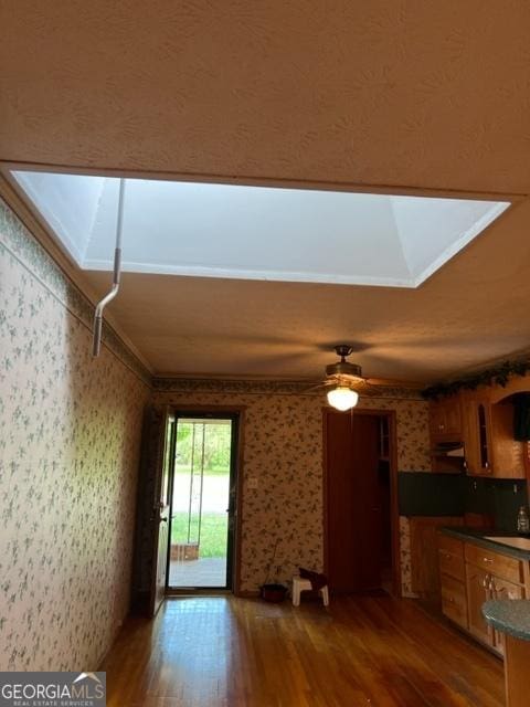 interior space with ornamental molding, dark wood-type flooring, ceiling fan, and a skylight