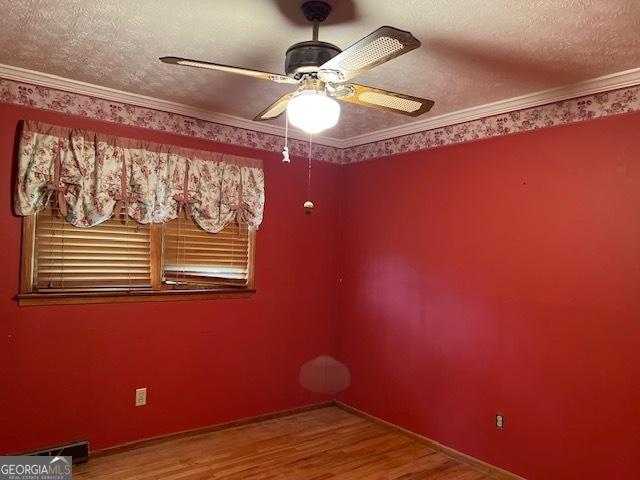 empty room with hardwood / wood-style floors, ornamental molding, a textured ceiling, and ceiling fan