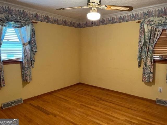 empty room with wood-type flooring, ornamental molding, and ceiling fan