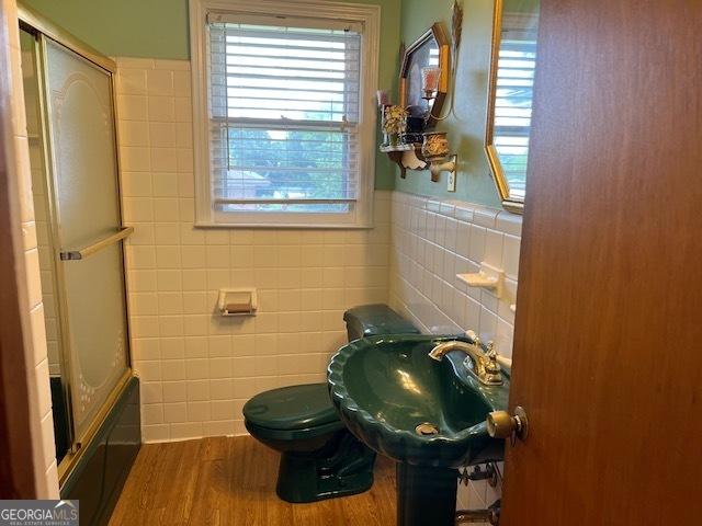 full bathroom with sink, enclosed tub / shower combo, tile walls, hardwood / wood-style floors, and toilet