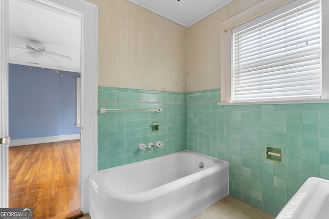 bathroom with hardwood / wood-style floors, a bathing tub, tile walls, and ceiling fan