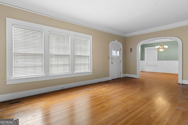 entrance foyer with crown molding, light hardwood / wood-style floors, and a chandelier