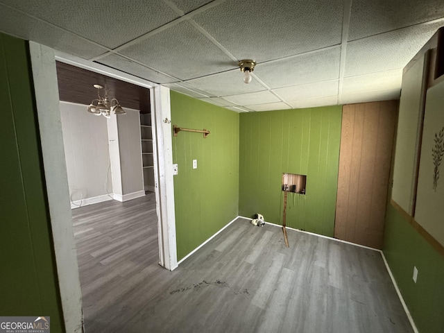 clothes washing area with wood walls, wood finished floors, and baseboards