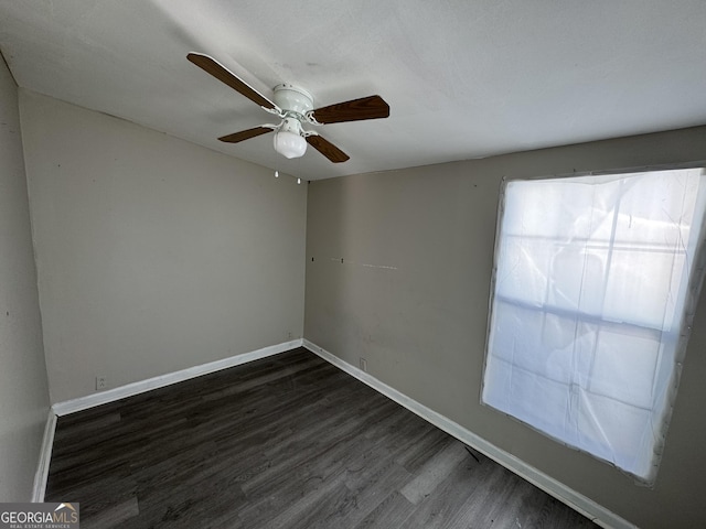 unfurnished room with baseboards, dark wood finished floors, and a ceiling fan