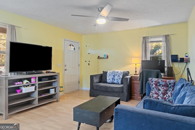 living room with ceiling fan, a textured ceiling, and light hardwood / wood-style floors