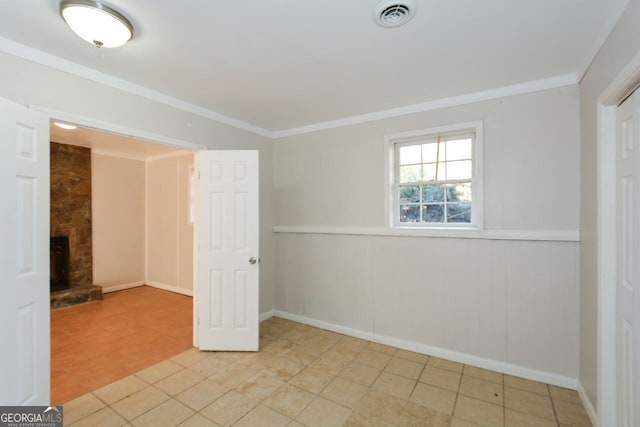 spare room featuring crown molding and a fireplace