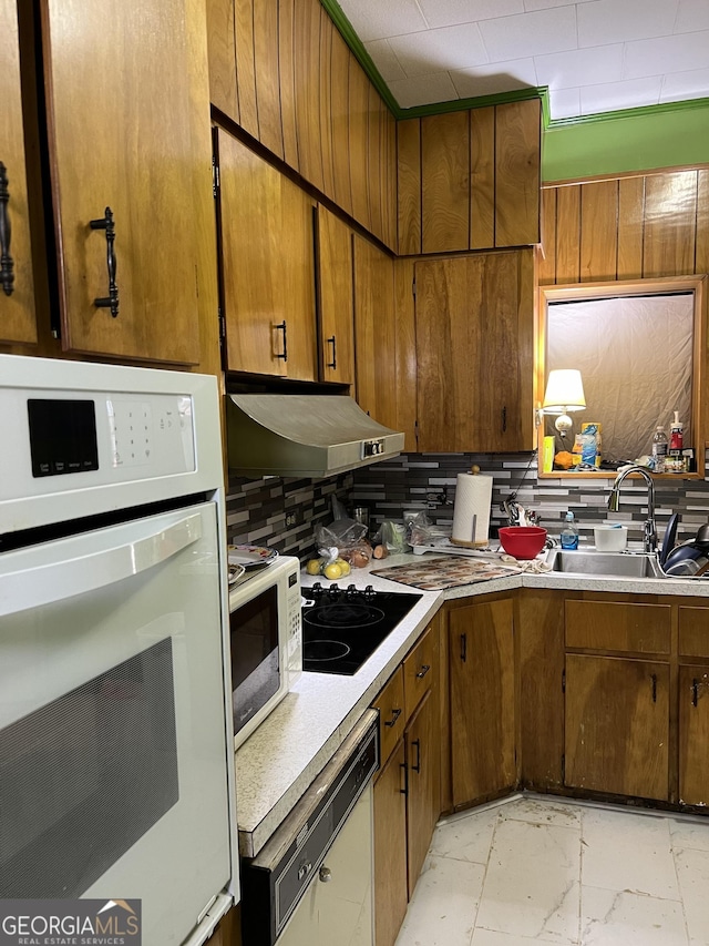 kitchen with sink, white appliances, and decorative backsplash