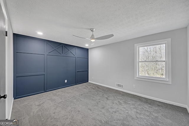 carpeted spare room featuring ceiling fan and a textured ceiling