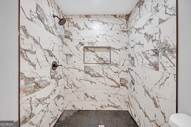 bathroom featuring a tile shower and toilet