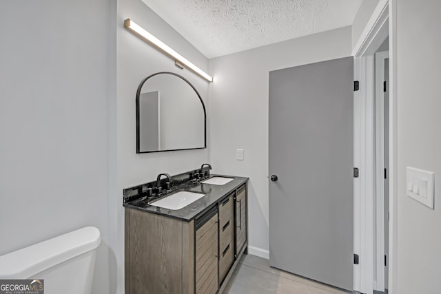 bathroom featuring vanity, a textured ceiling, and toilet