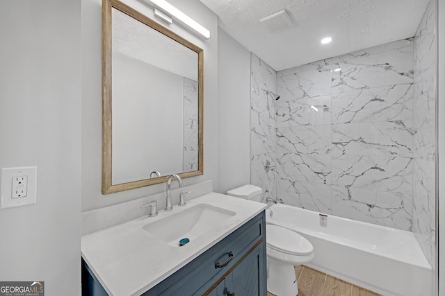 full bathroom with tiled shower / bath combo, vanity, wood-type flooring, a textured ceiling, and toilet