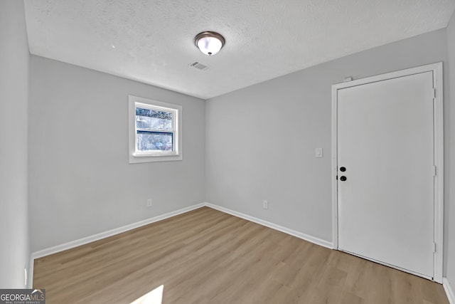 empty room with light hardwood / wood-style flooring and a textured ceiling