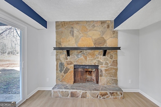 room details with a stone fireplace, hardwood / wood-style floors, and a textured ceiling