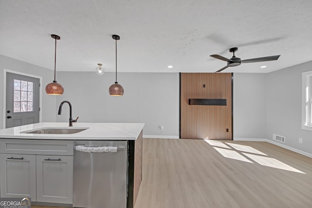 kitchen with sink, light hardwood / wood-style flooring, dishwasher, a kitchen island with sink, and decorative light fixtures