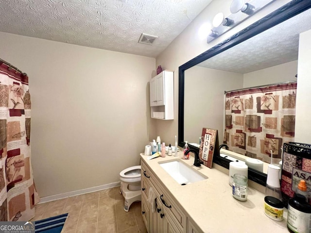 bathroom featuring vanity, tile patterned flooring, a textured ceiling, and toilet