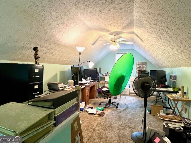 home office with vaulted ceiling, carpet flooring, ceiling fan, and a textured ceiling