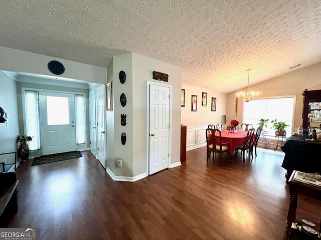 entryway featuring vaulted ceiling, dark wood-type flooring, a textured ceiling, and a chandelier