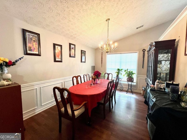 dining area featuring an inviting chandelier, dark hardwood / wood-style floors, vaulted ceiling, and a textured ceiling