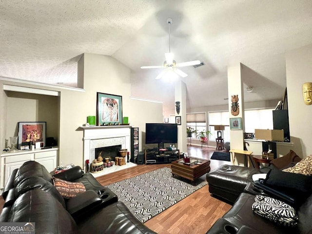 living room featuring lofted ceiling, hardwood / wood-style flooring, ceiling fan, a fireplace, and a textured ceiling