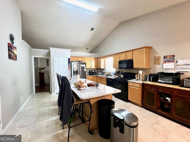 kitchen featuring sink, a breakfast bar area, black appliances, a center island, and backsplash