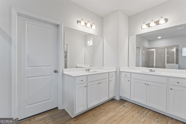 bathroom with wood-type flooring, vanity, and a shower with shower door