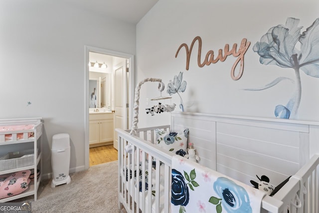 bedroom with ensuite bath, light carpet, and a crib