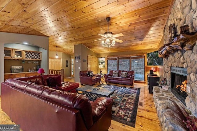 living room with vaulted ceiling, light wood-type flooring, wood ceiling, and a fireplace