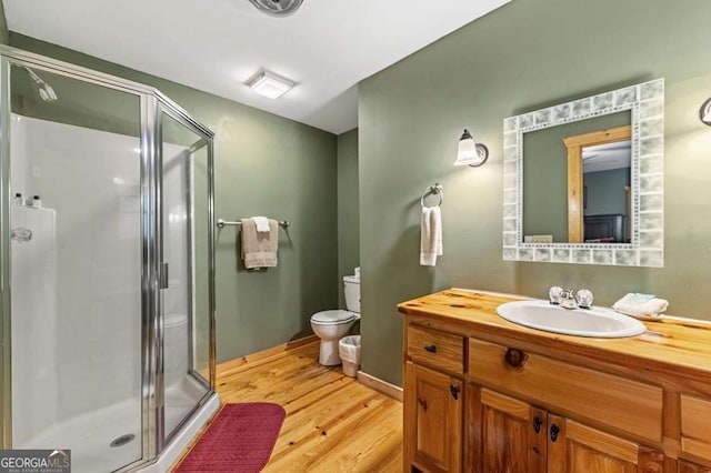 bathroom with vanity, hardwood / wood-style floors, a shower with shower door, and toilet