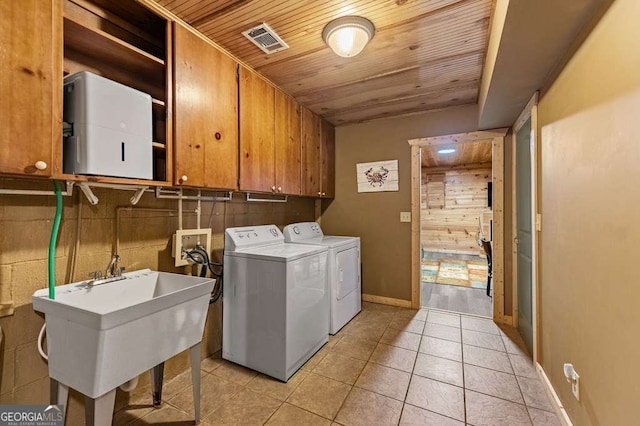 clothes washing area featuring light tile patterned flooring, sink, cabinets, independent washer and dryer, and wooden ceiling