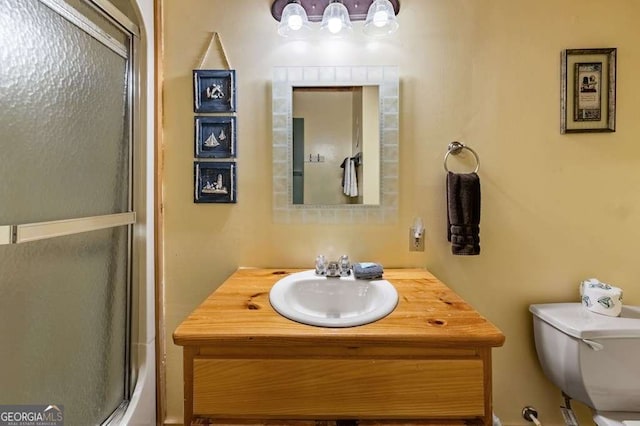 full bathroom with vanity, bath / shower combo with glass door, and toilet