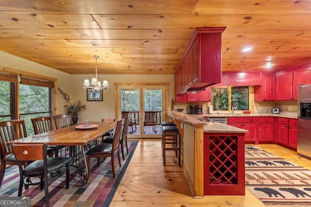 kitchen featuring wood ceiling, light hardwood / wood-style flooring, stainless steel appliances, and plenty of natural light