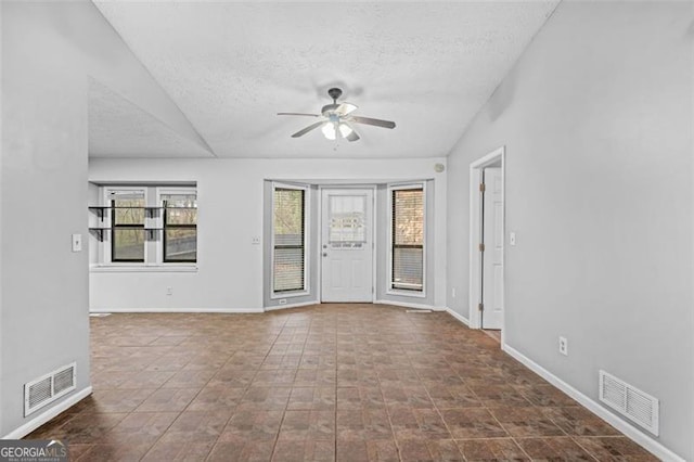 empty room featuring ceiling fan, vaulted ceiling, and a wealth of natural light