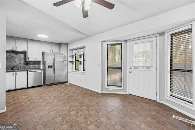 kitchen featuring lofted ceiling, sink, white cabinets, backsplash, and stainless steel appliances